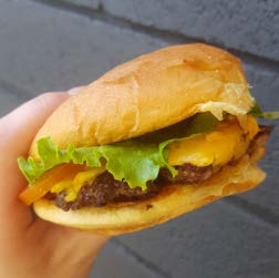 A cheeseburger is held in a close-up shot.