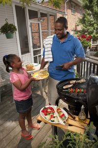 Image of father and daughter grilling outdoors.