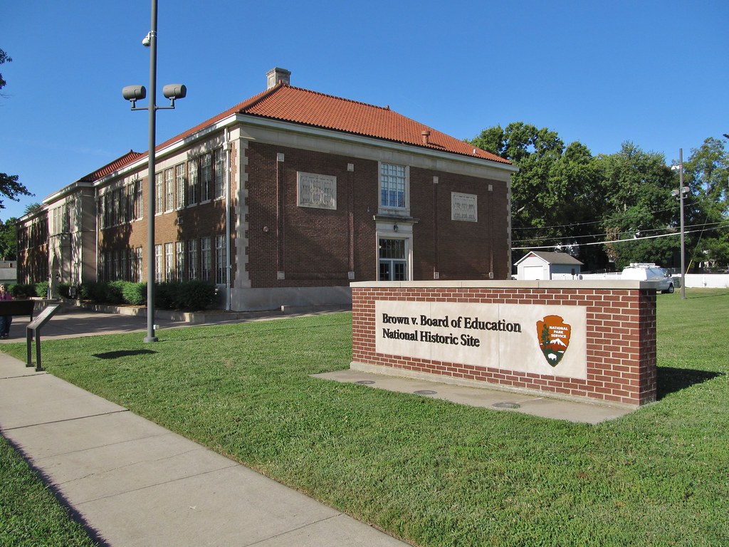 A sign reading "Brown v. Board of Education National Historic Site" sits in front of the original brick school building.
