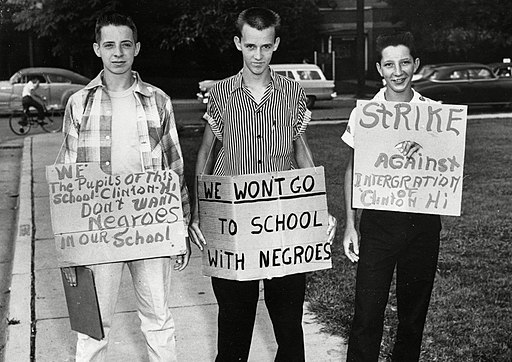 Three white teenager boys carrying protest signs against integration of schools